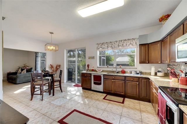 kitchen with appliances with stainless steel finishes, light stone countertops, light tile patterned flooring, pendant lighting, and sink