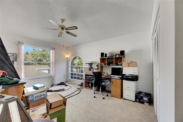 home office with ceiling fan, a textured ceiling, and light colored carpet