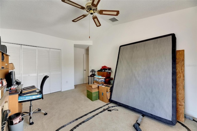 office area featuring a textured ceiling, vaulted ceiling, light colored carpet, and ceiling fan