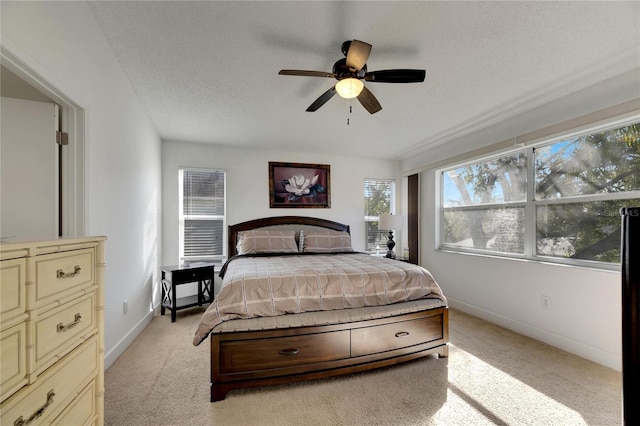 bedroom featuring light carpet, a textured ceiling, and ceiling fan