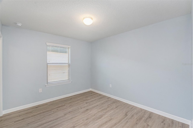 empty room with light hardwood / wood-style flooring and a textured ceiling