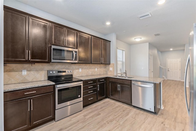 kitchen with stainless steel appliances, dark brown cabinets, light hardwood / wood-style flooring, and kitchen peninsula