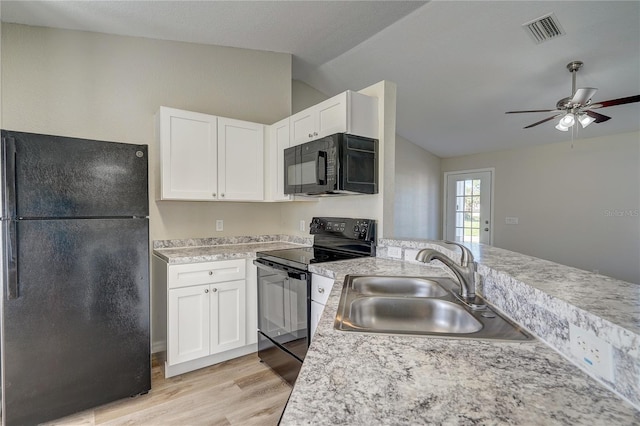 kitchen featuring light wood-type flooring, vaulted ceiling, sink, black appliances, and white cabinetry