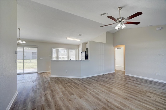 unfurnished living room with light hardwood / wood-style flooring, ceiling fan with notable chandelier, and lofted ceiling