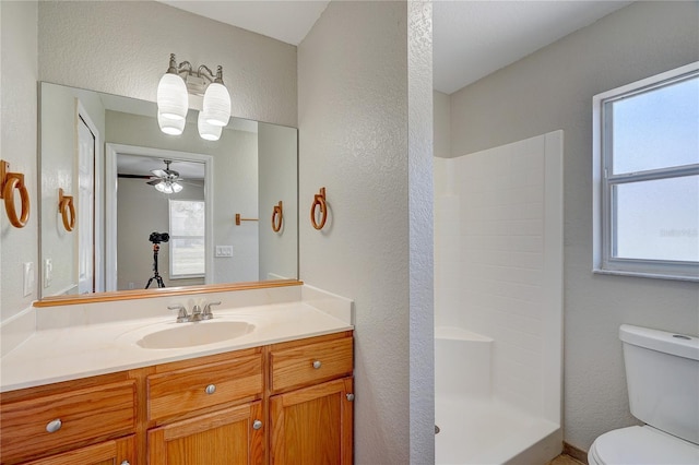 bathroom featuring ceiling fan, vanity, a healthy amount of sunlight, and toilet