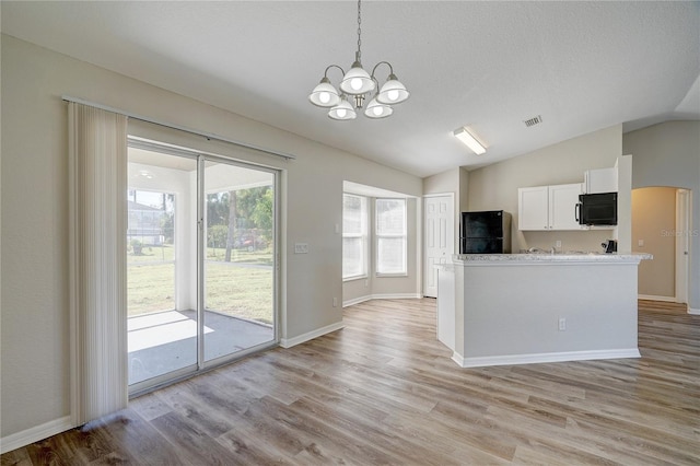 kitchen featuring white cabinets, a healthy amount of sunlight, lofted ceiling, and black appliances