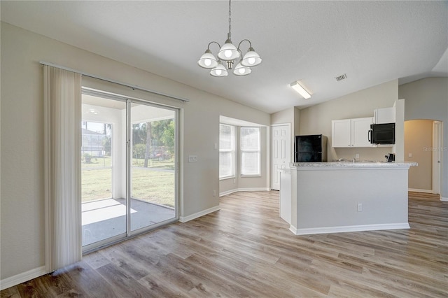 3776 Junction St, North Port, FL 34288 - kitchen with black appliances, lofted ceiling, light wood finished floors, a chandelier, and white cabinets
