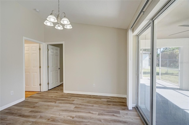 spare room featuring light hardwood / wood-style floors and ceiling fan with notable chandelier