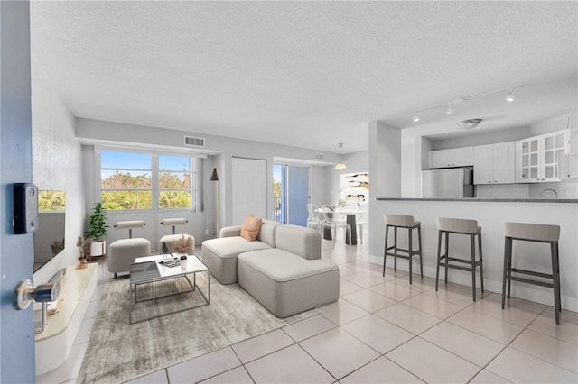 living room with a textured ceiling, light tile patterned flooring, and visible vents
