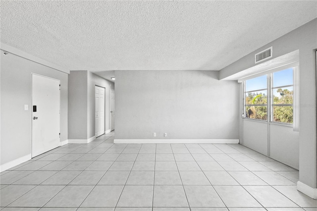 empty room featuring a textured ceiling and light tile patterned floors