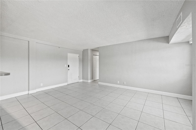 empty room featuring a textured ceiling, baseboards, light tile patterned floors, and visible vents
