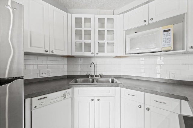 kitchen featuring a sink, tasteful backsplash, white appliances, white cabinets, and dark countertops