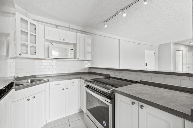 kitchen with dark countertops, stainless steel electric range, a textured ceiling, white cabinetry, and white microwave