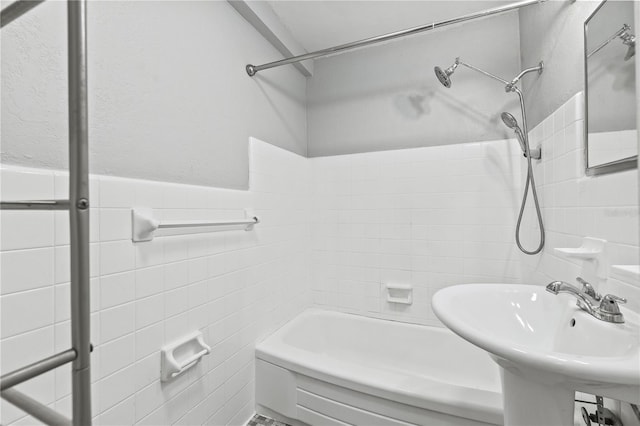 bathroom with tile walls, wainscoting, and a sink