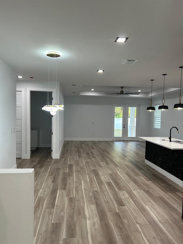 unfurnished living room with sink, hardwood / wood-style flooring, ceiling fan, and a textured ceiling