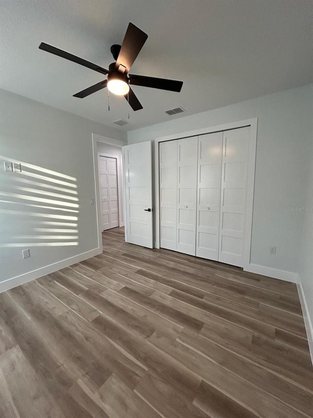 unfurnished bedroom with ceiling fan, wood-type flooring, and a closet