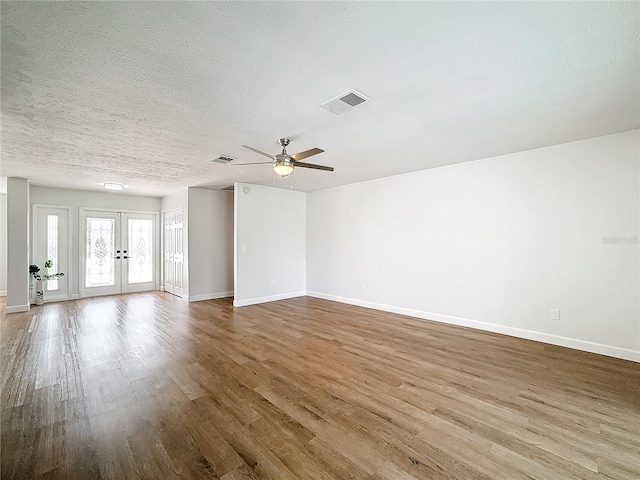 unfurnished room featuring french doors, a textured ceiling, light wood-type flooring, and ceiling fan