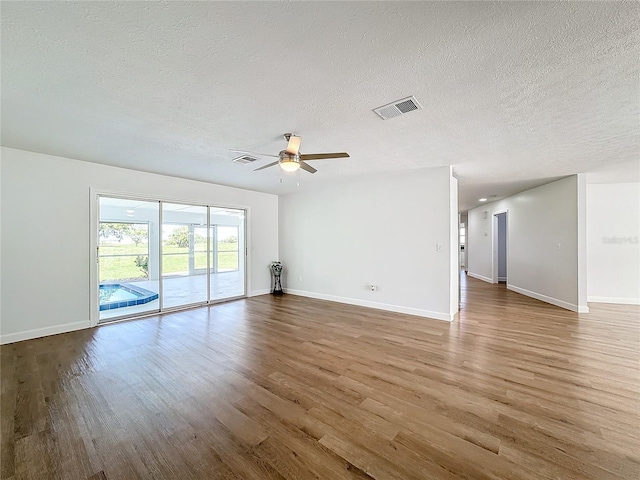 empty room with ceiling fan, wood-type flooring, and a textured ceiling