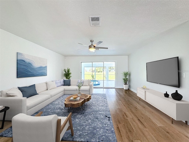 living room featuring a textured ceiling, hardwood / wood-style flooring, and ceiling fan