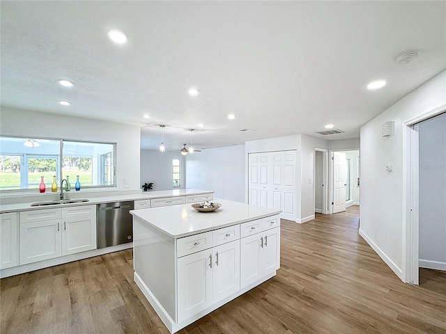 kitchen with sink, dishwasher, light wood-type flooring, a kitchen island, and white cabinets