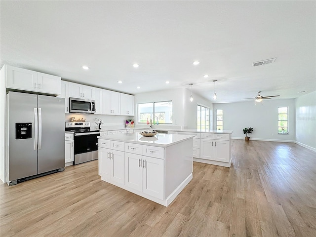 kitchen featuring appliances with stainless steel finishes, light hardwood / wood-style flooring, white cabinets, and a healthy amount of sunlight