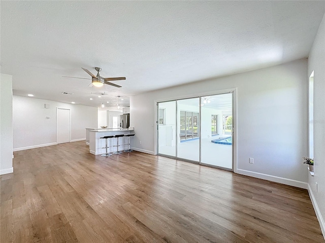 unfurnished living room with hardwood / wood-style floors, a textured ceiling, and ceiling fan