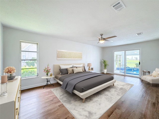 bedroom featuring hardwood / wood-style flooring, multiple windows, access to outside, and ceiling fan