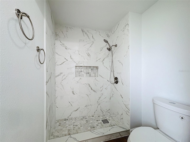 bathroom featuring a tile shower and toilet