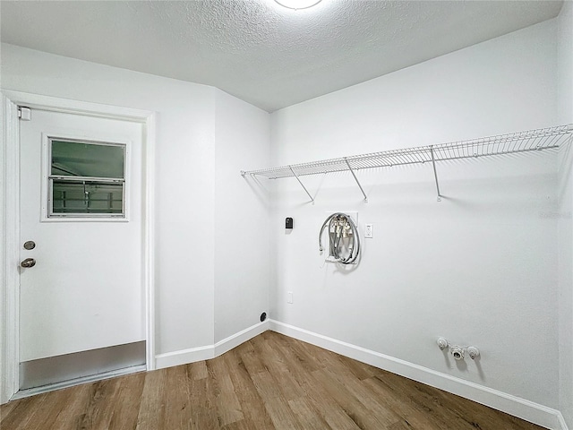 laundry room with hookup for a gas dryer, a textured ceiling, and hardwood / wood-style flooring