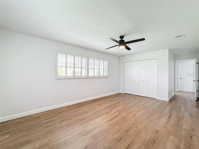 unfurnished bedroom featuring a closet, a textured ceiling, light wood-type flooring, and ceiling fan