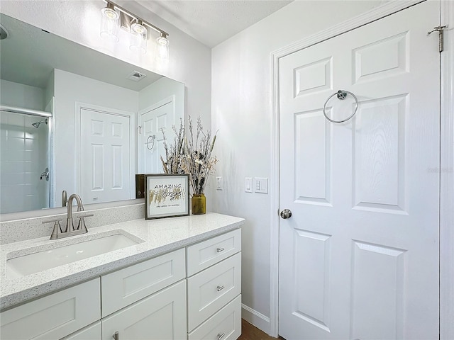 bathroom featuring a shower with door and vanity