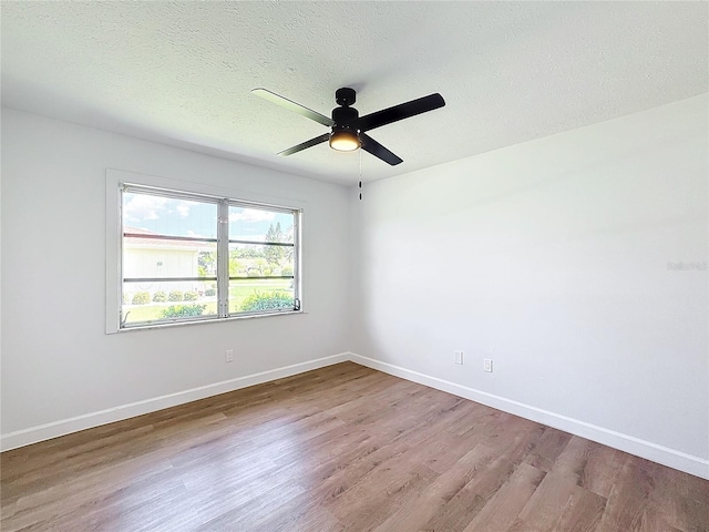 unfurnished room with ceiling fan, a textured ceiling, and light wood-type flooring