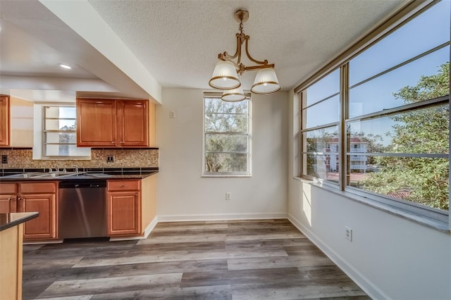 kitchen featuring backsplash, dark hardwood / wood-style flooring, stainless steel dishwasher, and decorative light fixtures