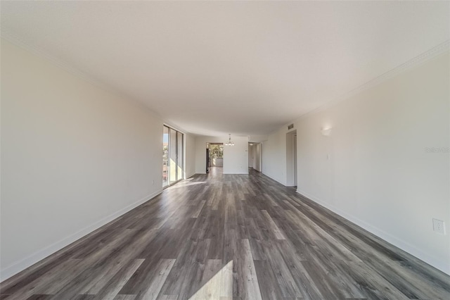 empty room with crown molding, an inviting chandelier, and dark hardwood / wood-style flooring