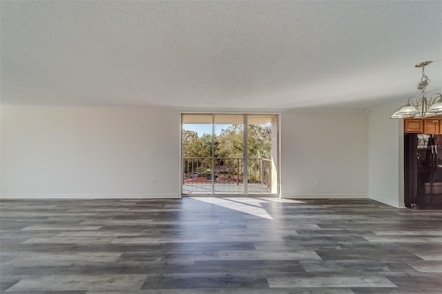 unfurnished room featuring dark wood-type flooring, a textured ceiling, an inviting chandelier, and a wall of windows