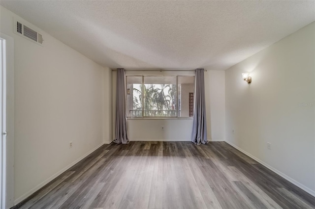 empty room featuring dark wood-type flooring and a textured ceiling