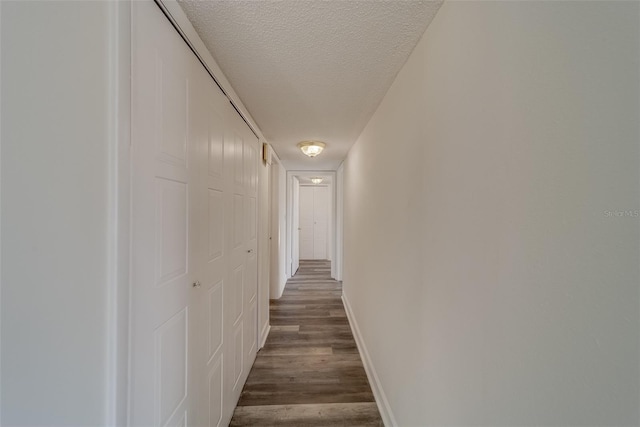 corridor featuring dark wood-type flooring and a textured ceiling