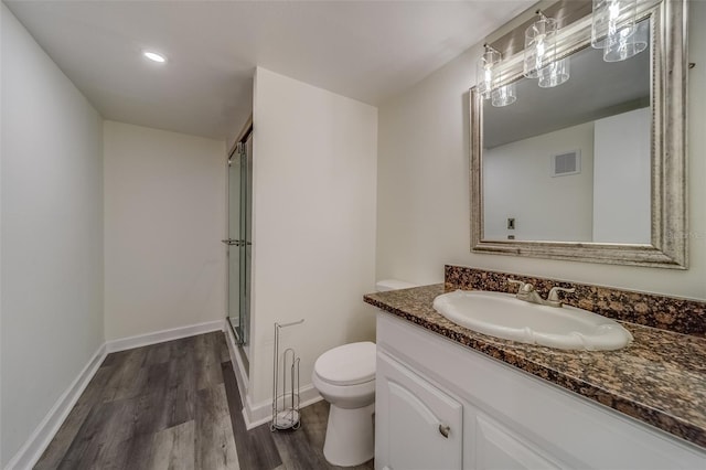 bathroom with toilet, a shower with shower door, hardwood / wood-style floors, and vanity