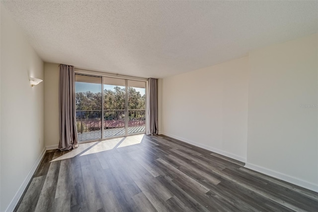 spare room with a textured ceiling, dark hardwood / wood-style flooring, and a wall of windows