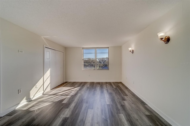 empty room featuring a textured ceiling and dark wood-type flooring