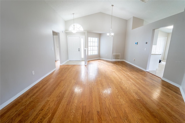 interior space with high vaulted ceiling, a chandelier, and light wood-type flooring