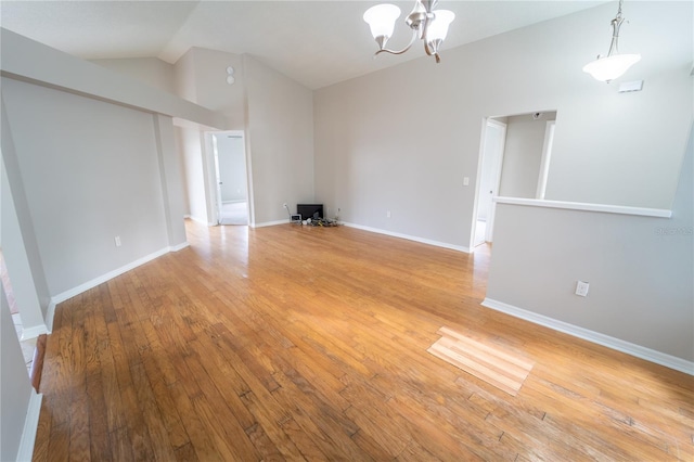 unfurnished living room with light hardwood / wood-style floors, lofted ceiling, and a chandelier