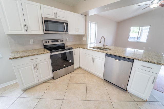 kitchen featuring kitchen peninsula, appliances with stainless steel finishes, vaulted ceiling, sink, and white cabinets