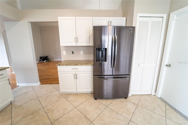 kitchen with light stone countertops, backsplash, stainless steel fridge with ice dispenser, white cabinetry, and light tile patterned flooring