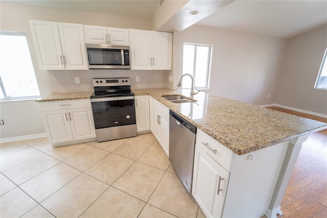 kitchen with white cabinets, sink, decorative backsplash, kitchen peninsula, and stainless steel appliances