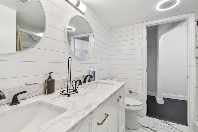 bathroom featuring toilet, vanity, and wooden walls