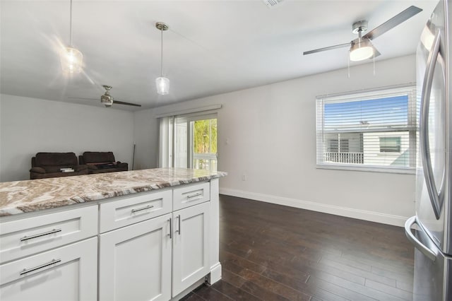 kitchen featuring dark wood-type flooring, stainless steel fridge, light stone countertops, decorative light fixtures, and white cabinets