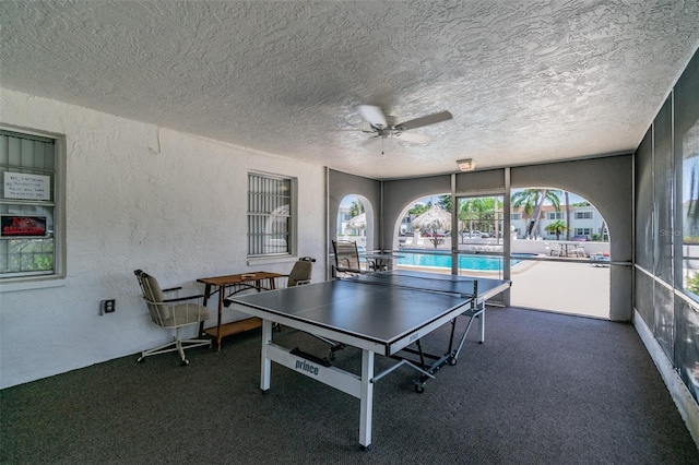 rec room with a textured ceiling and dark colored carpet