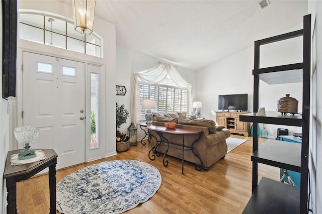 foyer with high vaulted ceiling, a textured ceiling, a chandelier, and wood-type flooring