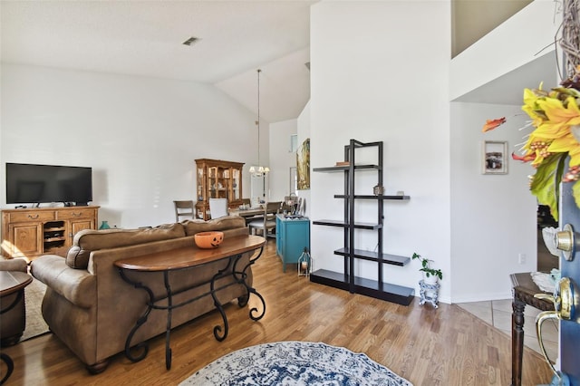 living room featuring hardwood / wood-style floors, high vaulted ceiling, and an inviting chandelier